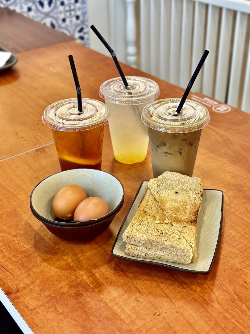 A table with three iced drinks, two eggs, and toast, showcasing a classic breakfast spread.