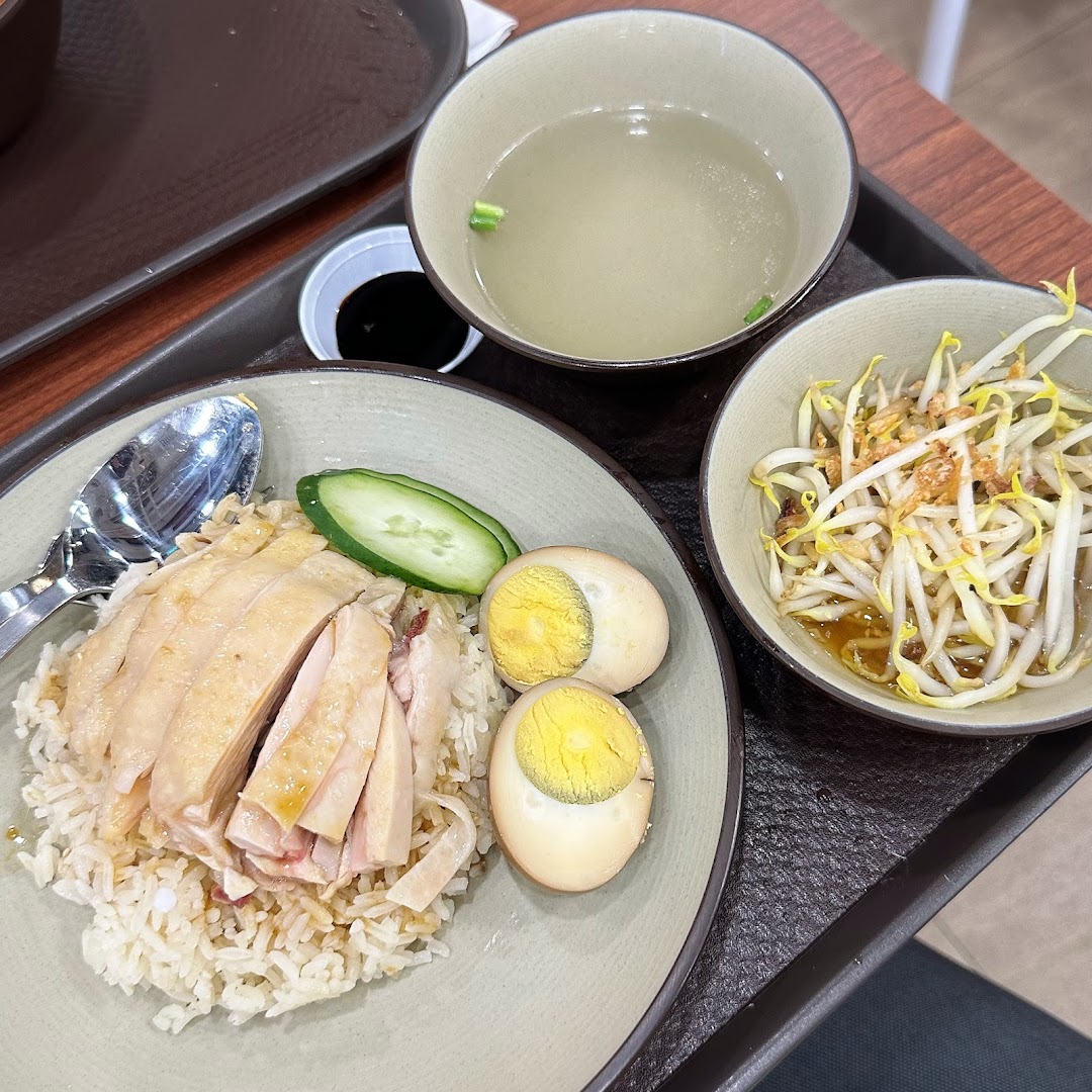 A plate of Hainanese chicken rice with eggs, bean sprouts, and clear soup.