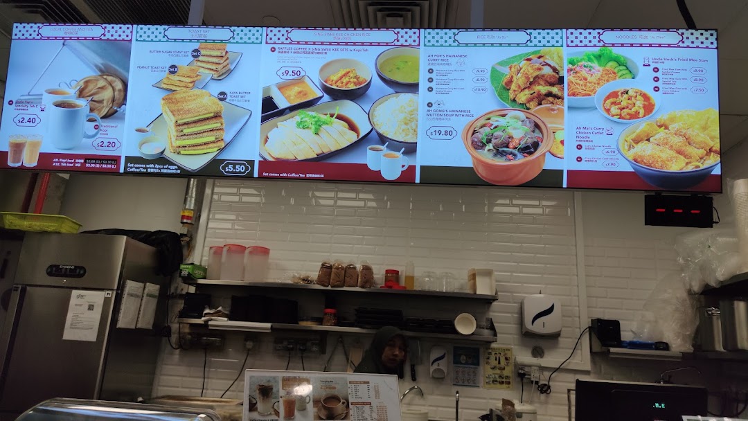 A digital menu board displaying various coffee, toast, rice, and noodle dishes with prices.