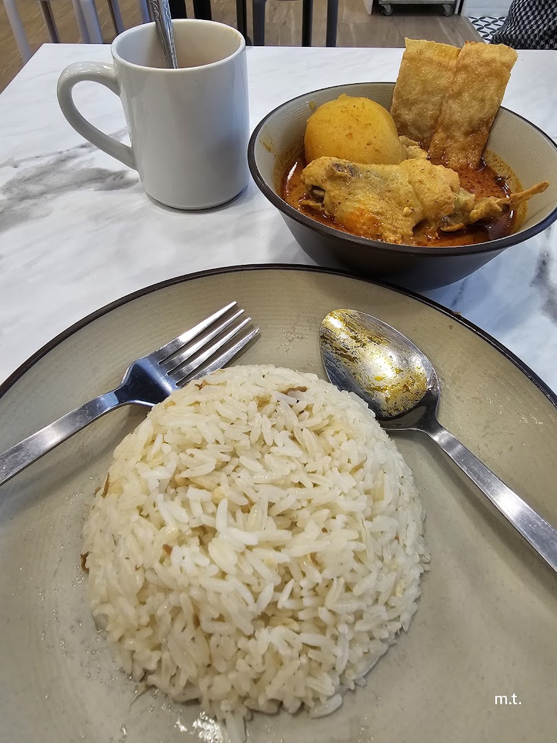 A delicious bowl of curry chicken with rice and a drink on a marble table.