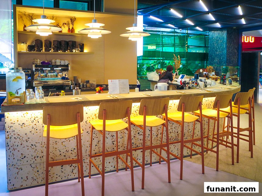A modern coffee bar with a long counter, bar stools, and a barista station.
