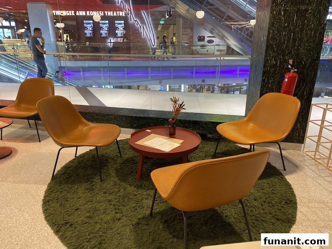 A cozy seating area with modern chairs and a table, offering a view of the bustling mall interior.