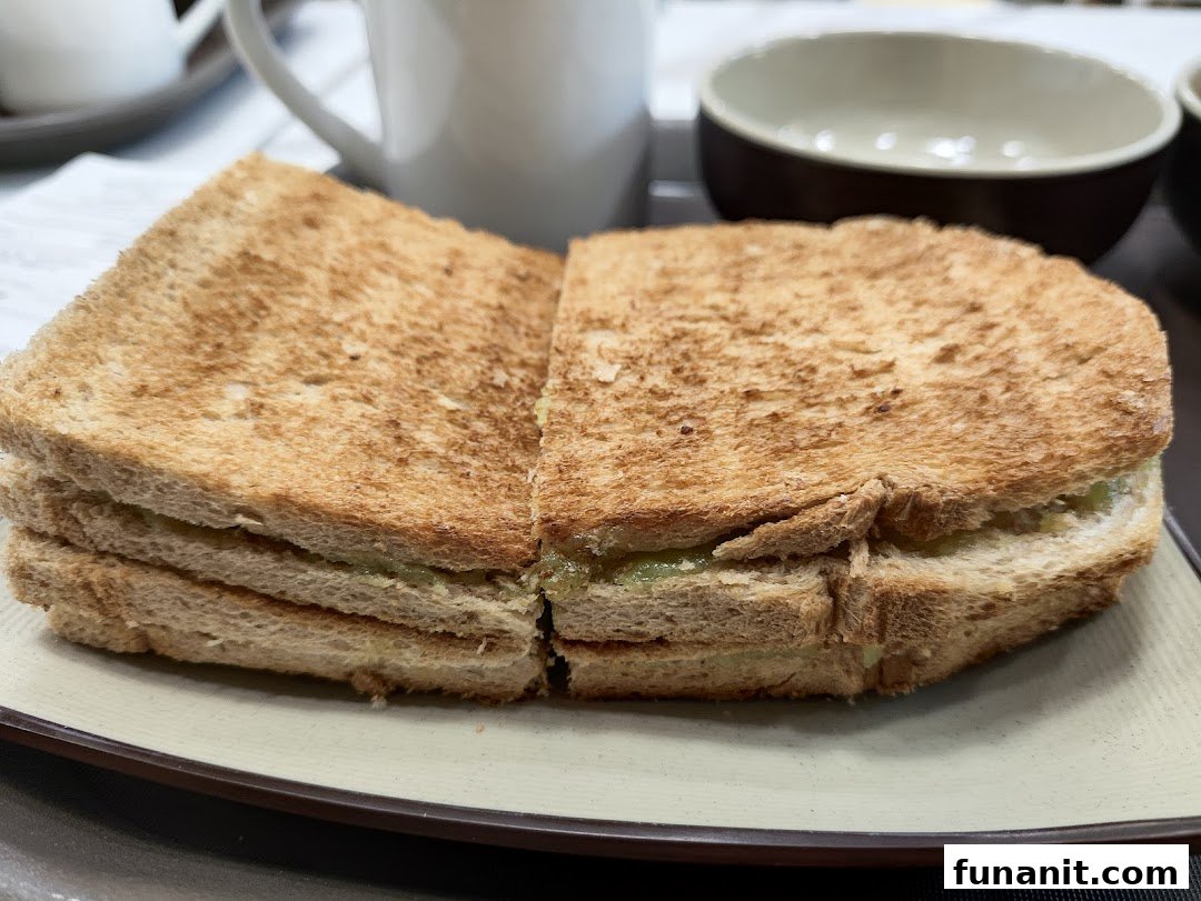 A close-up of golden-brown kaya toast served on a plate with a beverage in the background.