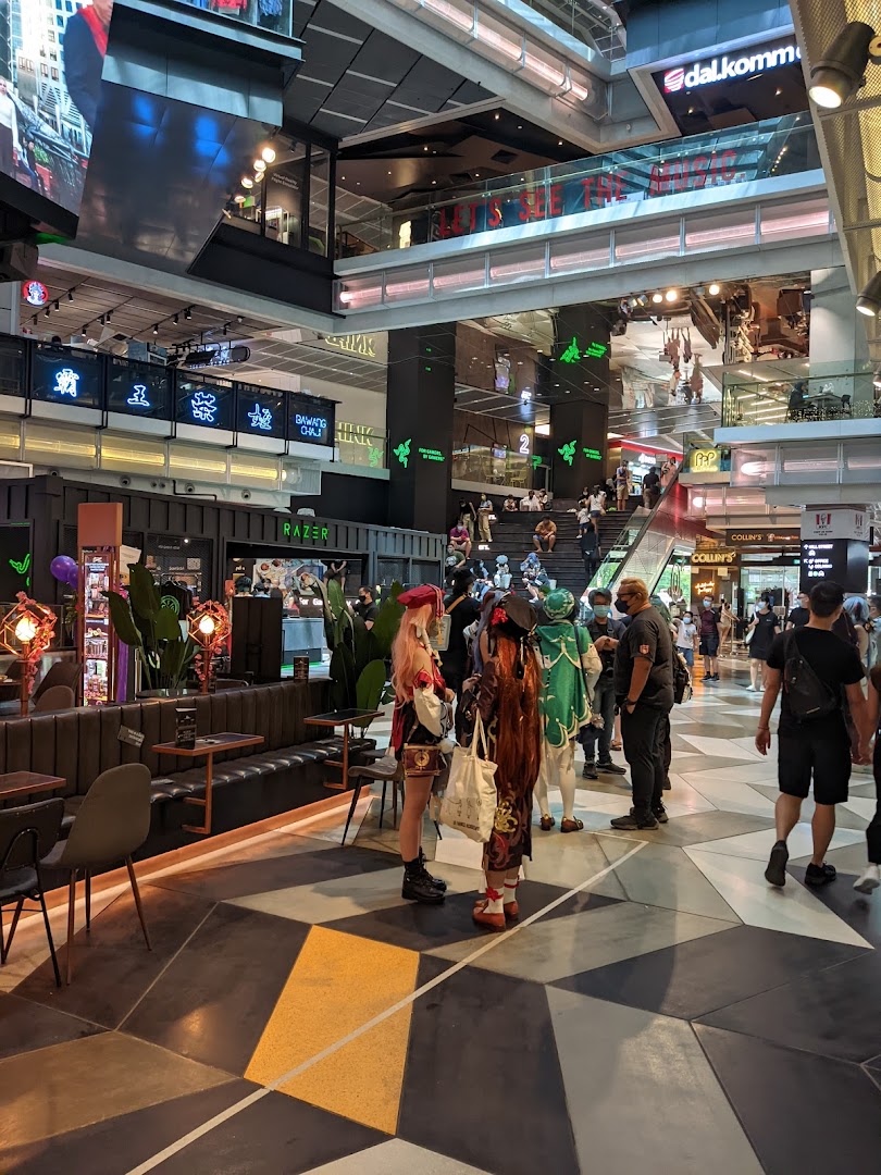 A vibrant mall interior featuring the RazerStore, with shoppers and cosplayers enjoying the atmosphere.