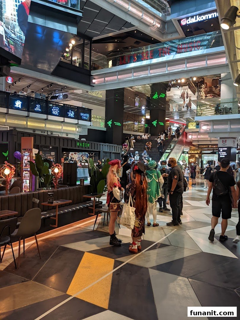 A vibrant mall interior featuring the RazerStore, with shoppers and cosplayers enjoying the atmosphere.