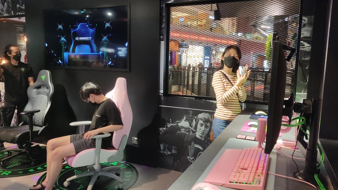 Customers interact with gaming chairs and peripherals in the RazerStore, showcasing products and an immersive experience.