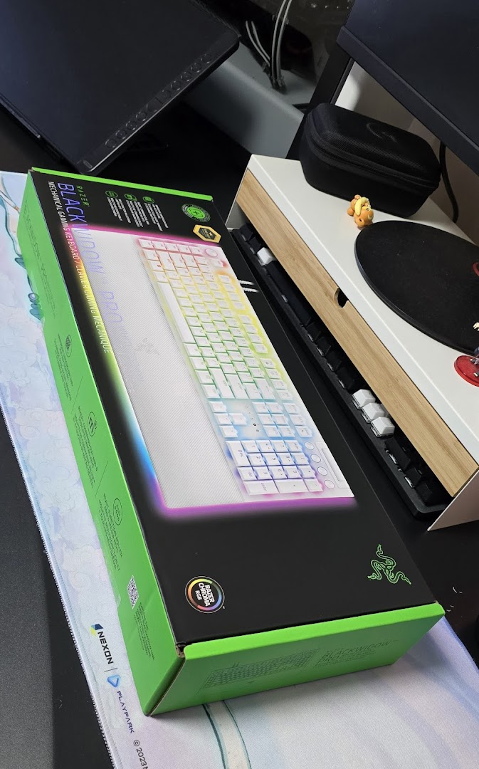 A Razer BlackWidow Pro mechanical gaming keyboard box is displayed on a desk with other tech accessories.
