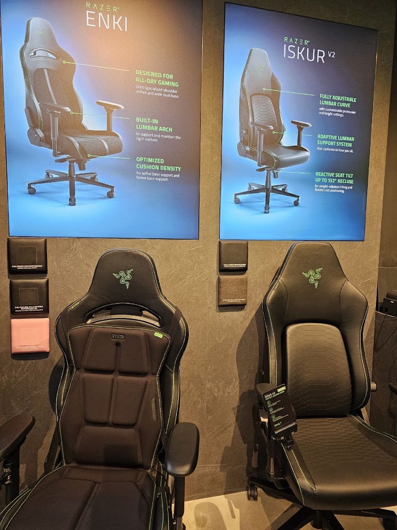 Two Razer gaming chairs, Enki and Iskur V2, displayed with feature posters in-store.