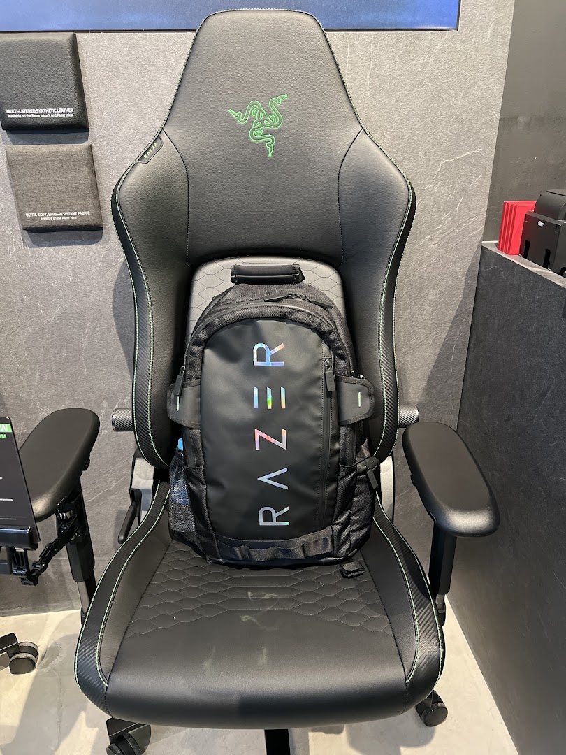 A black Razer gaming chair with a Razer backpack on it, showcasing products in the store.