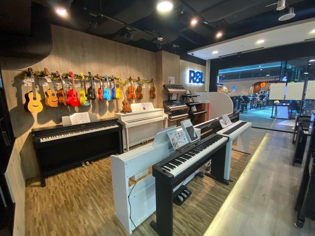 An interior view of a music store showcasing a wide array of pianos, keyboards, ukuleles, and violins.