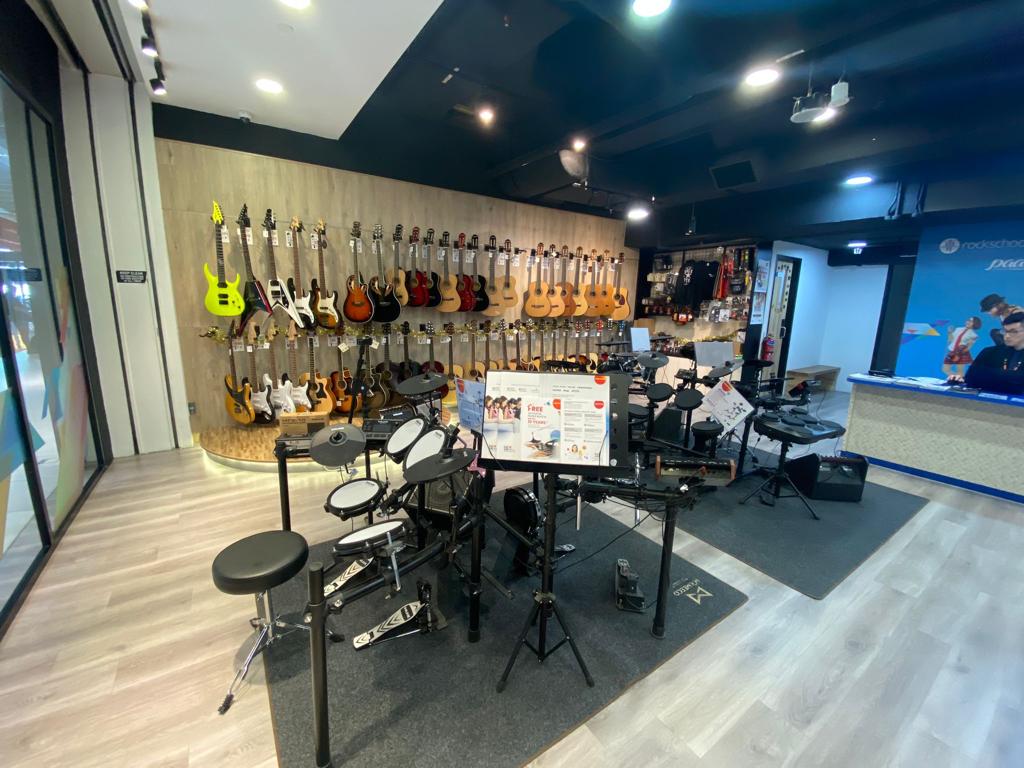 An interior view of Rockschool, RSL London, showcasing a wide array of guitars, ukuleles, and electronic drum kits.