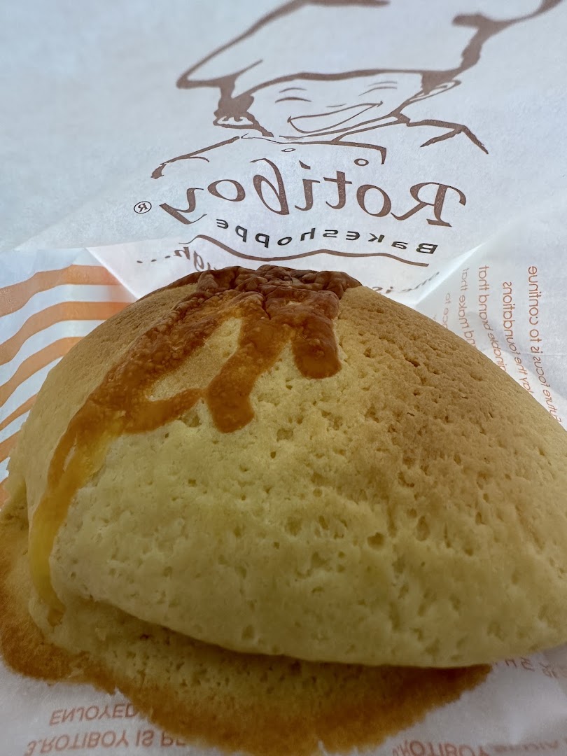 A close-up of a freshly baked Rotiboy bun in its signature paper bag.