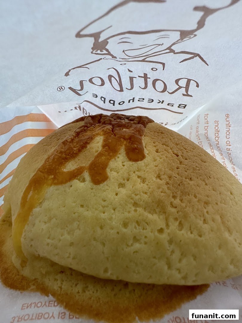 A close-up of a freshly baked Rotiboy bun in its signature paper bag.