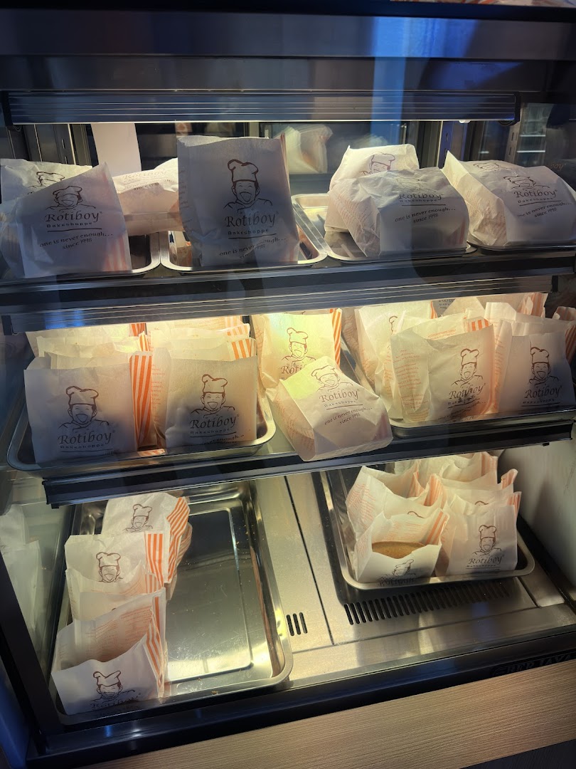 A display case filled with freshly baked Rotiboy buns in branded paper bags, ready for purchase.