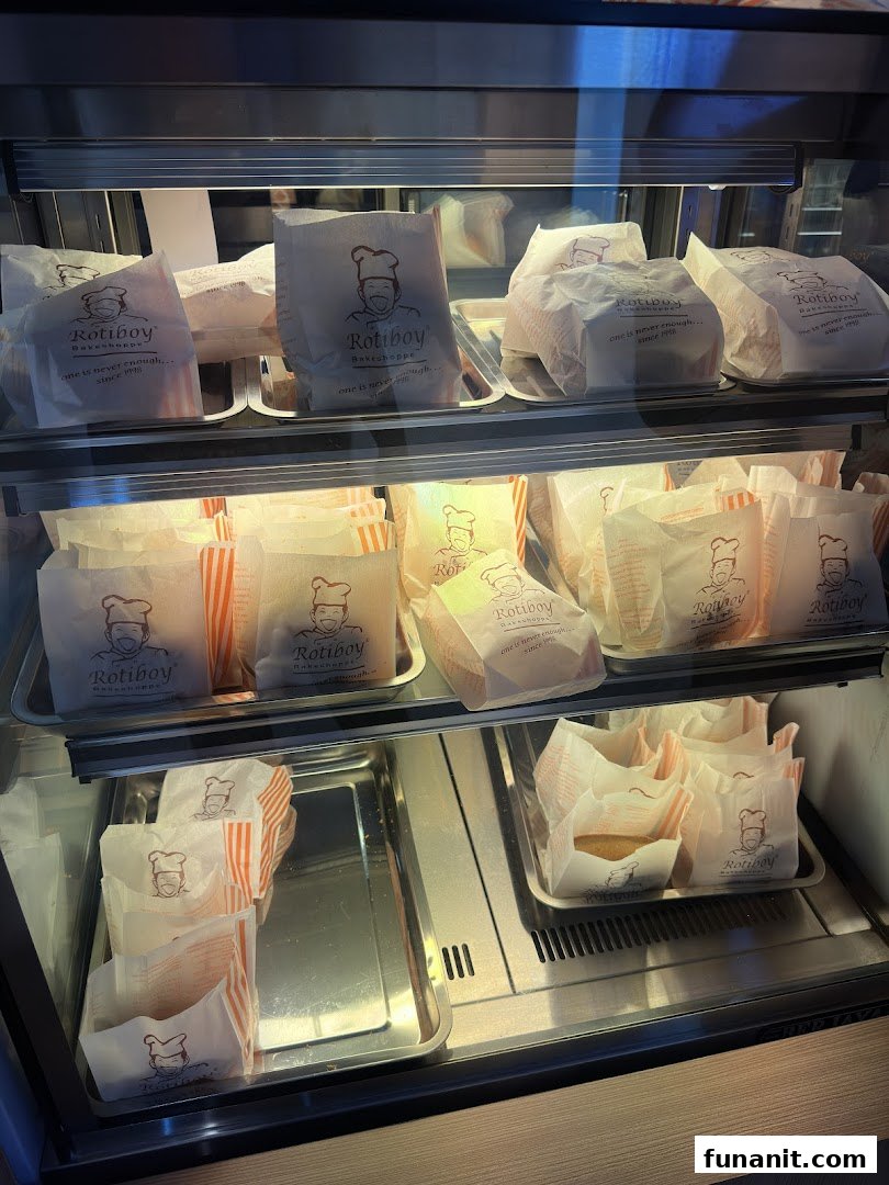 A display case filled with freshly baked Rotiboy buns in branded paper bags, ready for purchase.
