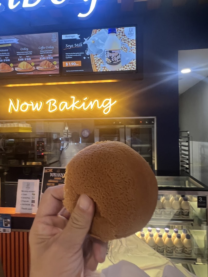 A digital menu board at Rotiboy displaying beverages and baked goods with prices.
