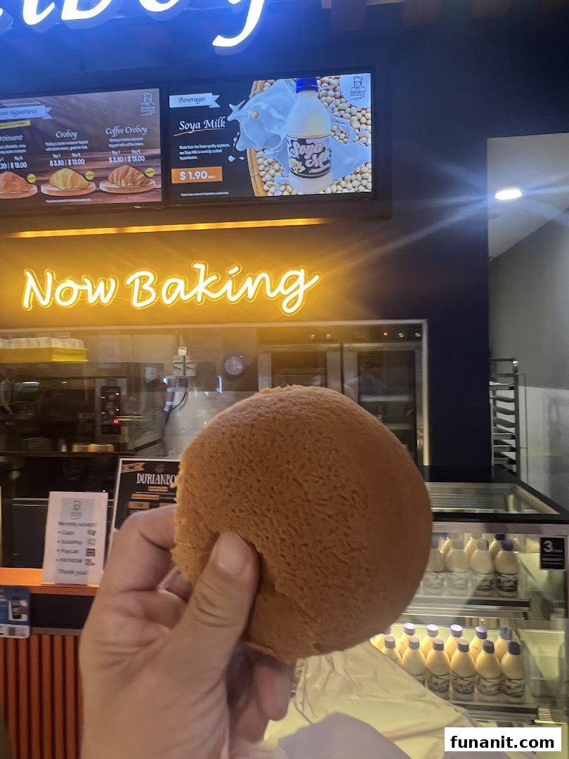 A digital menu board at Rotiboy displaying beverages and baked goods with prices.