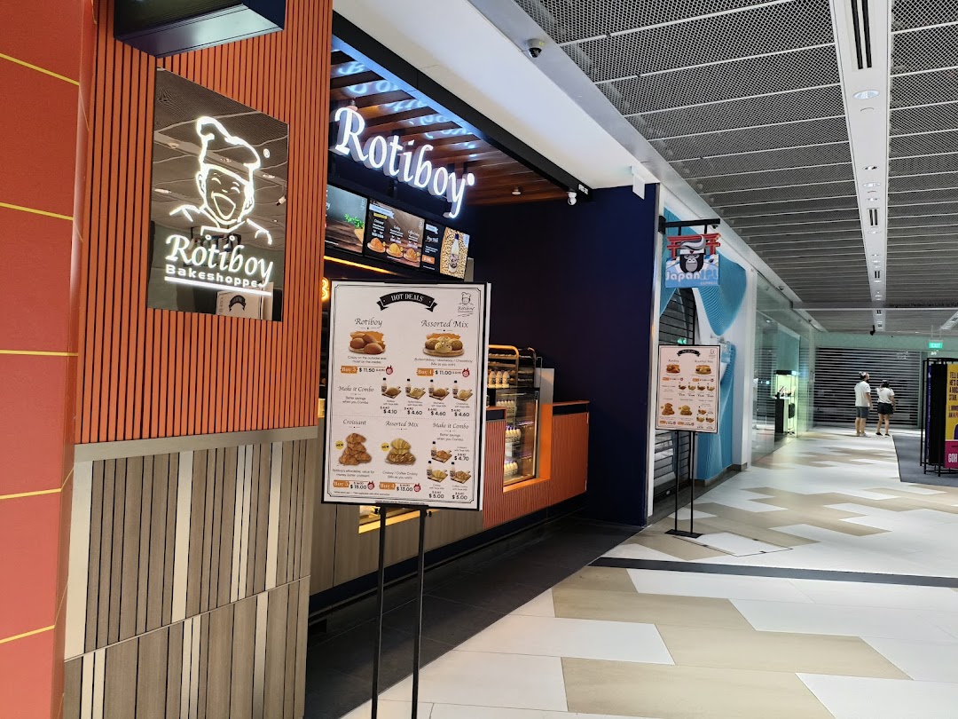 The Rotiboy Bakeshoppe storefront in a mall, featuring its logo, signage, and a display stand.