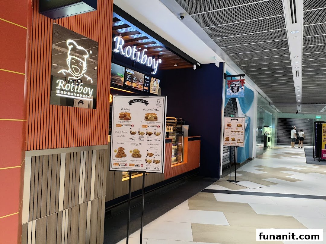 The Rotiboy Bakeshoppe storefront in a mall, featuring its logo, signage, and a display stand.