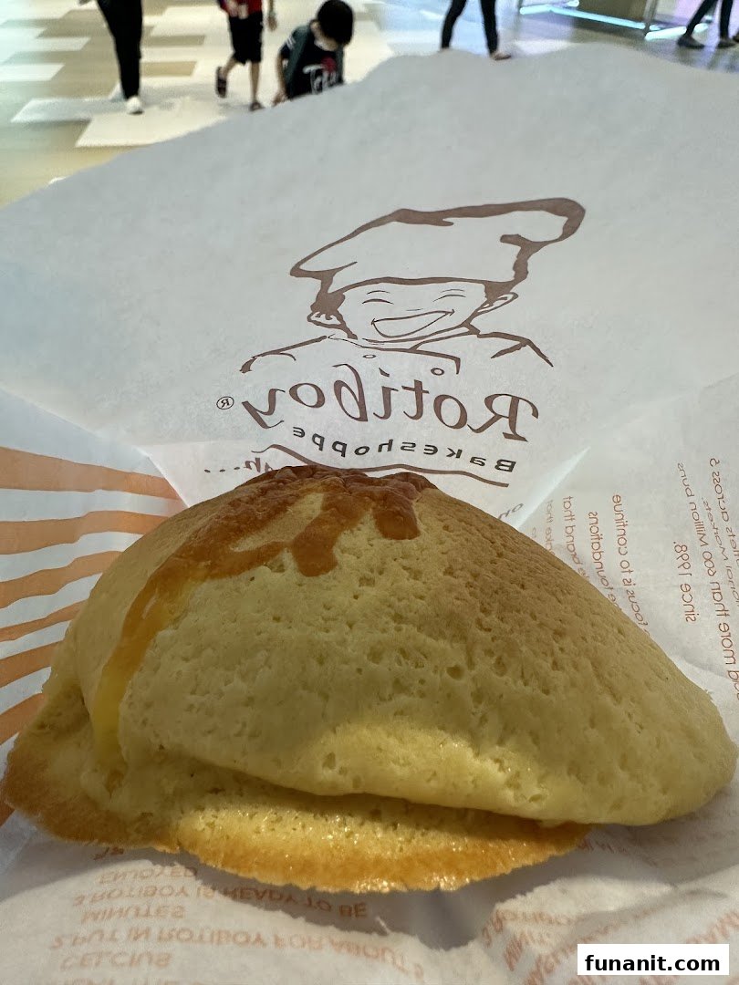 A freshly baked Rotiboy bun rests in its branded paper bag, showcasing its golden crust.