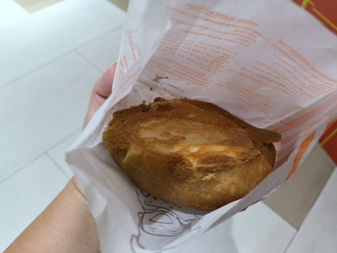 A hand holds a freshly baked Rotiboy bun in its signature paper bag.