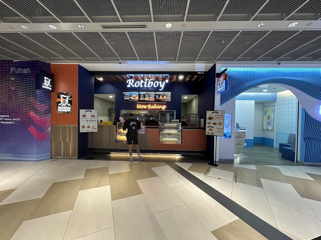 The Rotiboy shop front in a mall, featuring its signature branding and a customer at the counter.