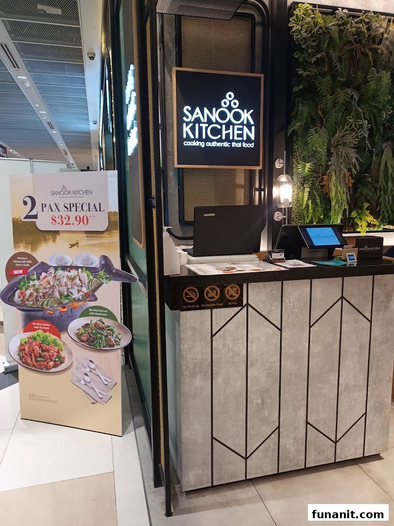 The shop front of Sanook Kitchen, featuring its logo, a promotional stand, and a modern counter.