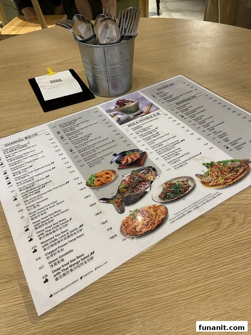 A detailed menu from Sanook Kitchen, displaying various Thai dishes and beverages on a wooden table.