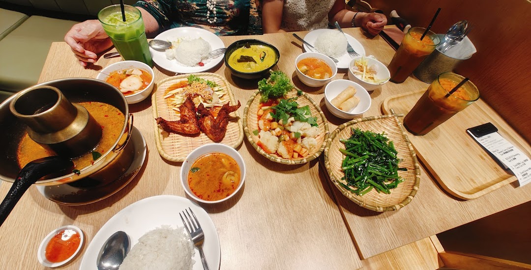 A vibrant spread of authentic Thai dishes and drinks laid out on a wooden table.