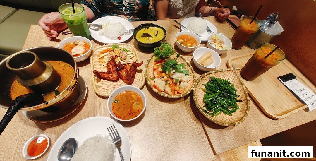 A vibrant spread of authentic Thai dishes and drinks laid out on a wooden table.