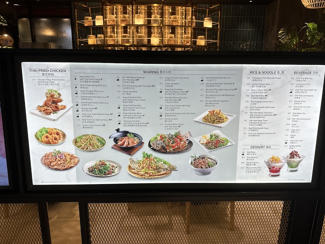 A brightly lit menu board displaying a wide array of Thai dishes and beverages with images.