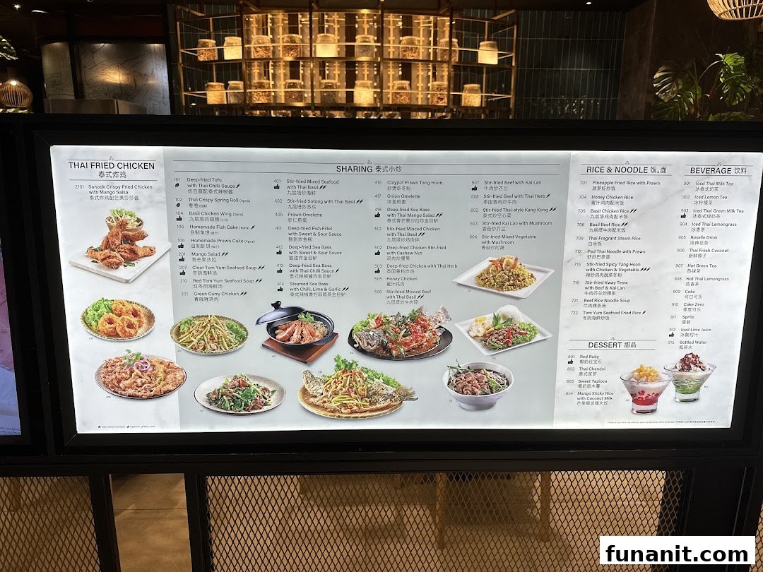 A brightly lit menu board displaying a wide array of Thai dishes and beverages with images.