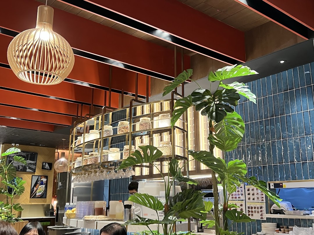 An interior view of Sanook Kitchen, featuring modern decor, a counter, and hanging shelves with ingredients.