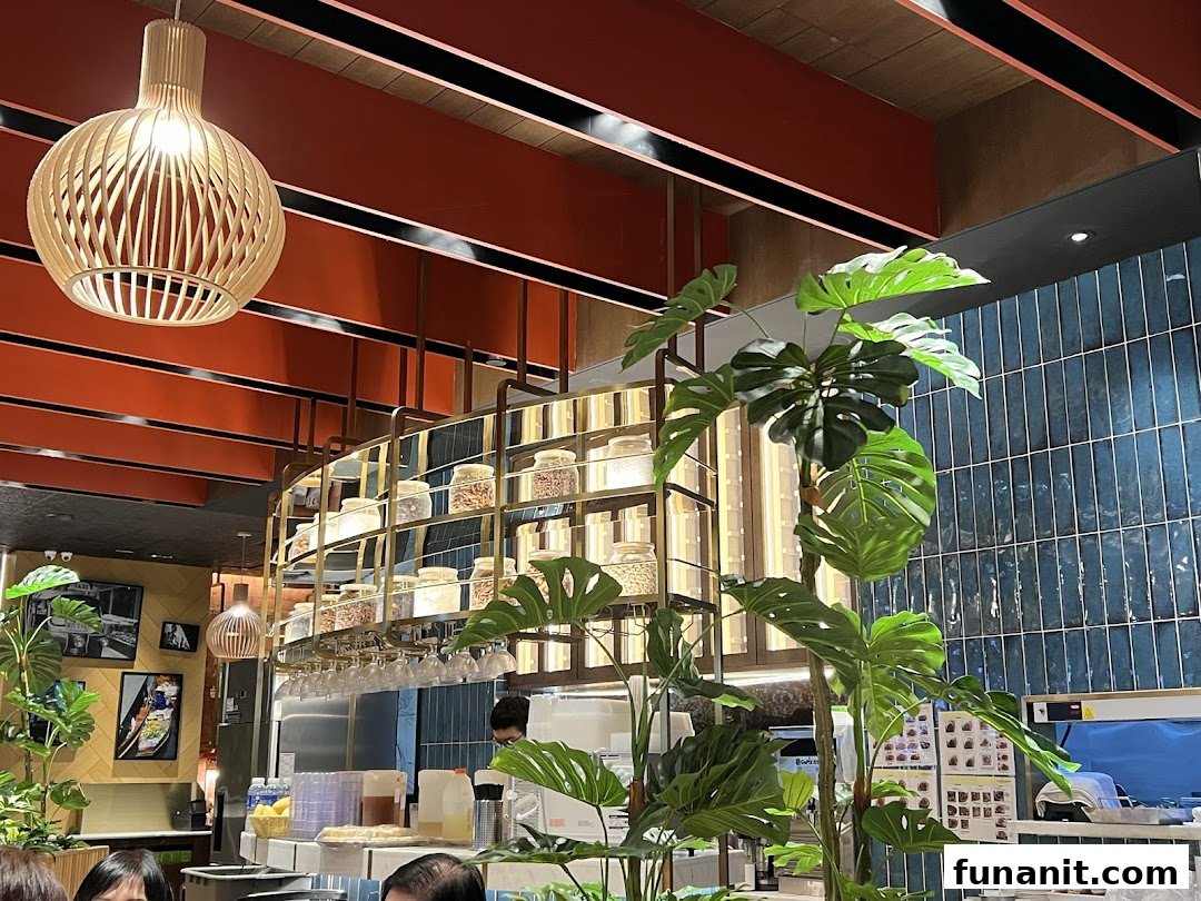 An interior view of Sanook Kitchen, featuring modern decor, a counter, and hanging shelves with ingredients.