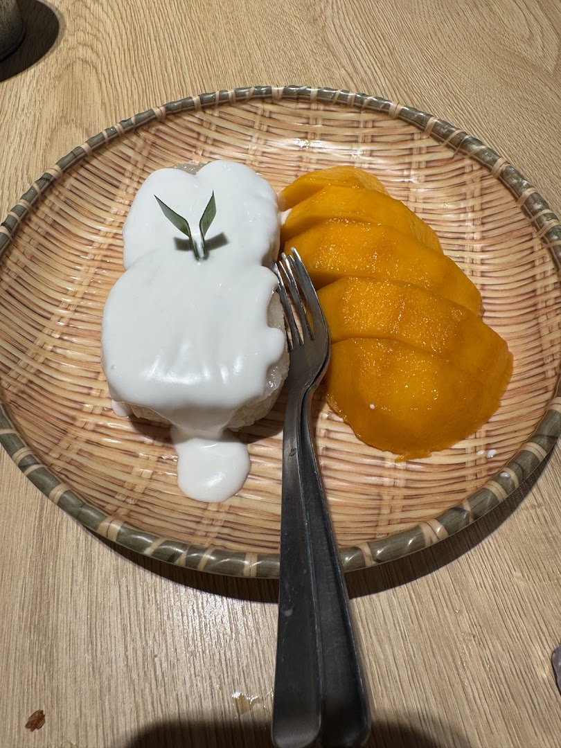 A delicious plate of mango sticky rice with coconut cream and fresh mango slices.