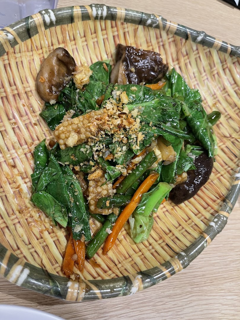 A vibrant stir-fried vegetable dish with mushrooms and crispy toppings served in a woven basket.
