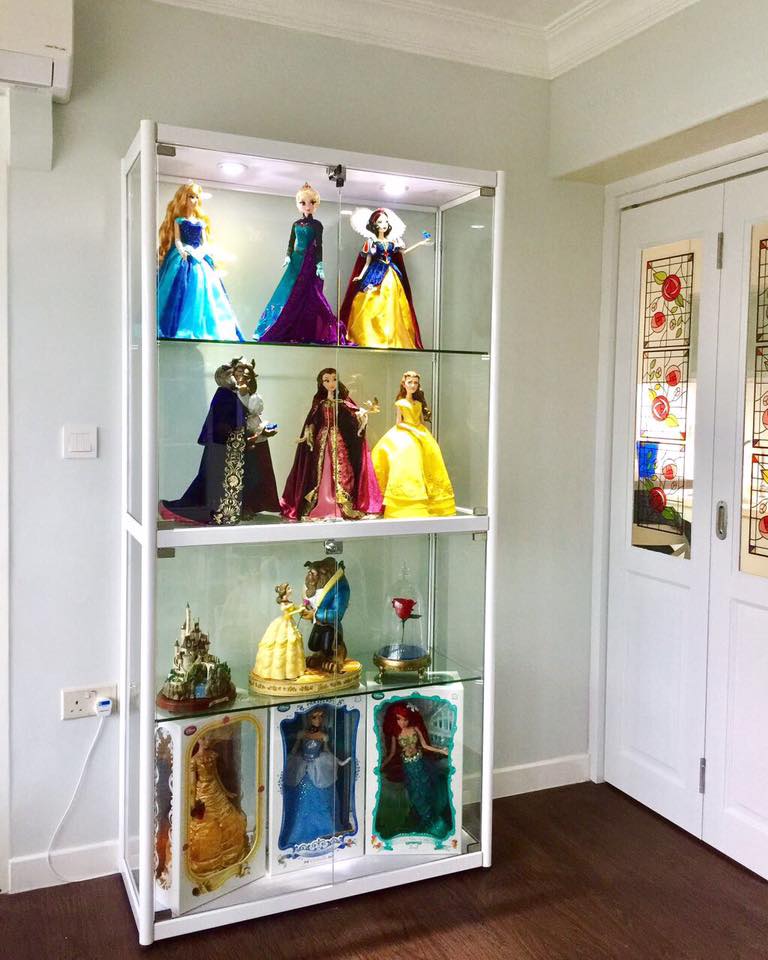 A brightly lit display cabinet showcasing a collection of popular character dolls and figurines.