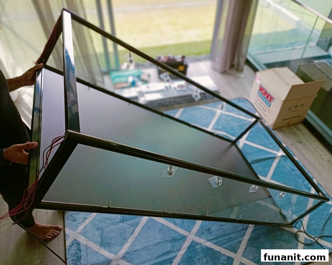 A person assembling or moving a black-framed glass display case on a patterned rug.
