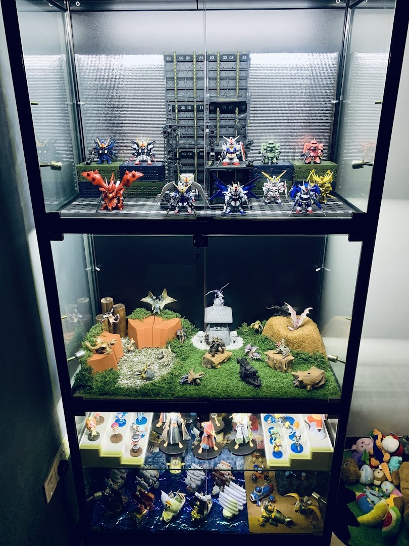 A multi-tiered display case showcasing various anime figures, robot models, and detailed dioramas.
