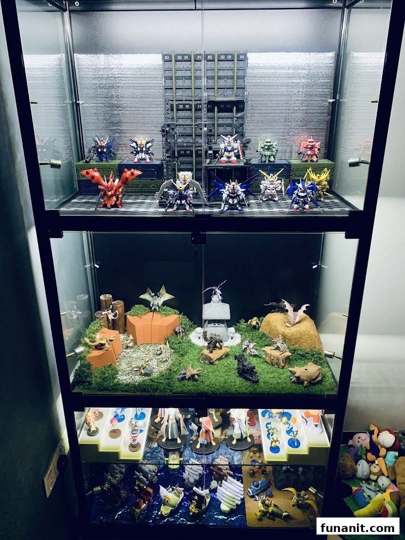 A multi-tiered display case showcasing various anime figures, robot models, and detailed dioramas.