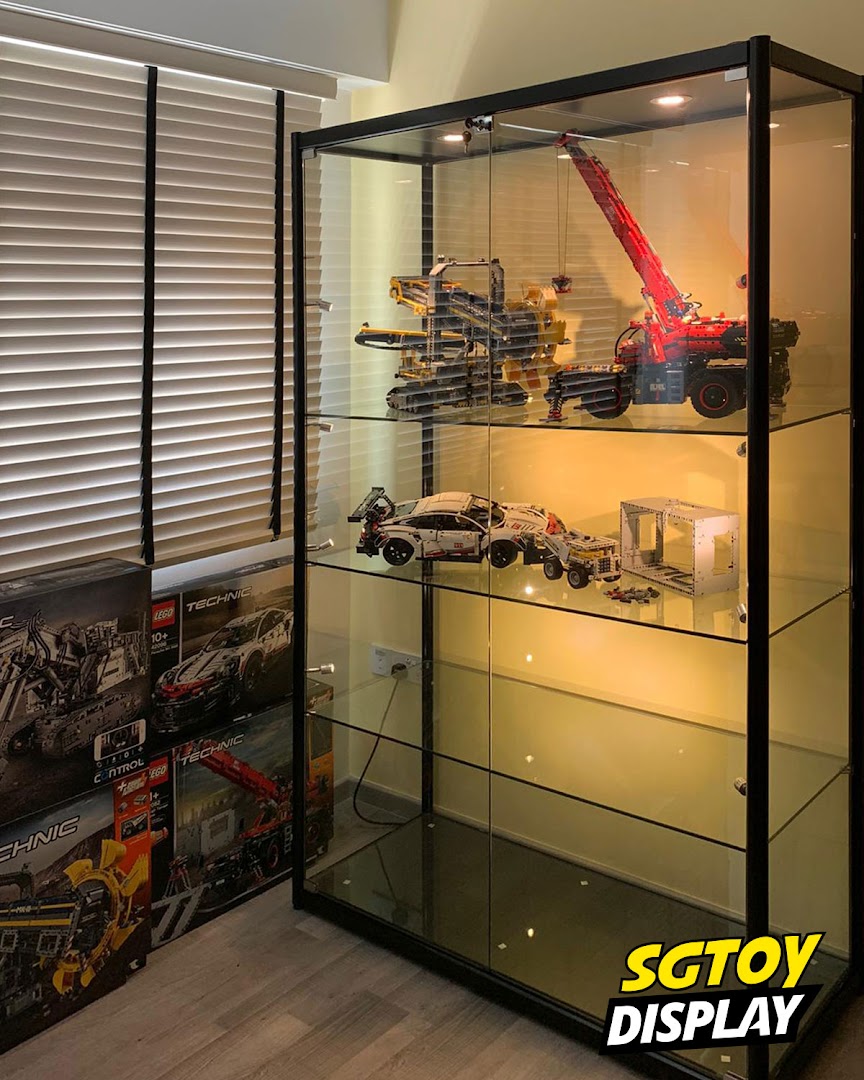 A glass display cabinet showcasing intricate LEGO Technic models and product boxes.