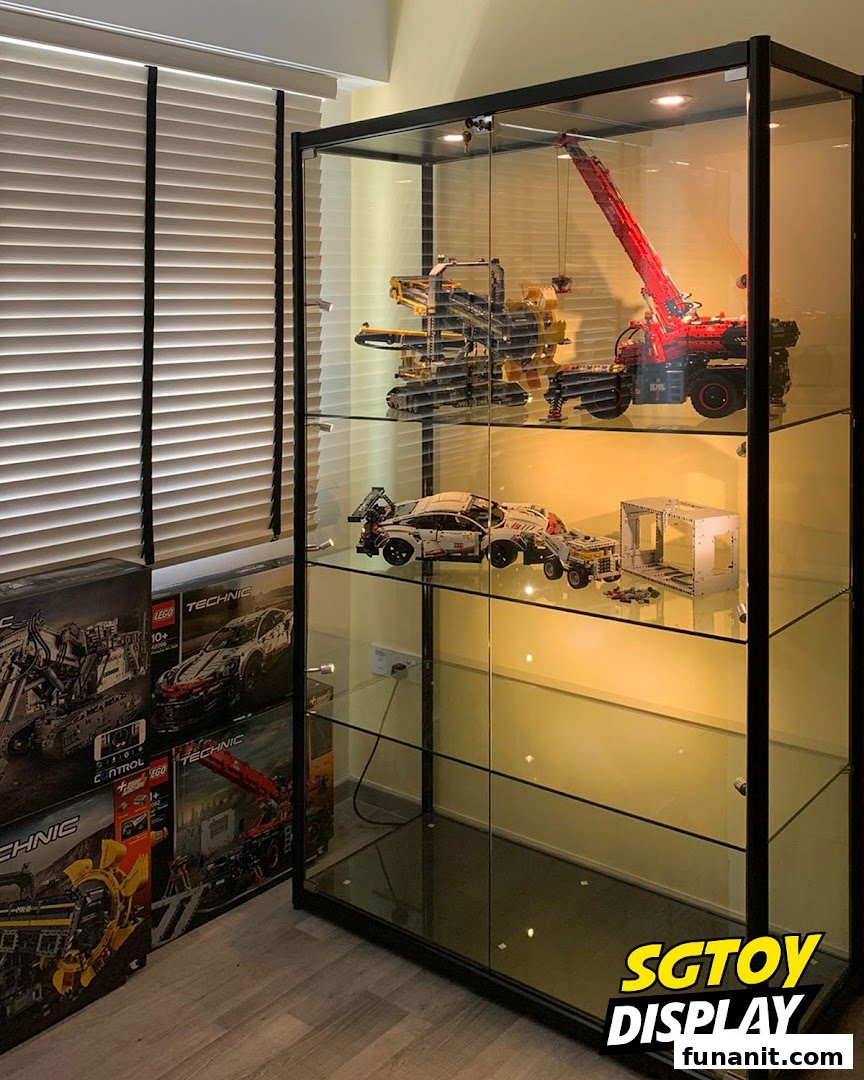 A glass display cabinet showcasing intricate LEGO Technic models and product boxes.