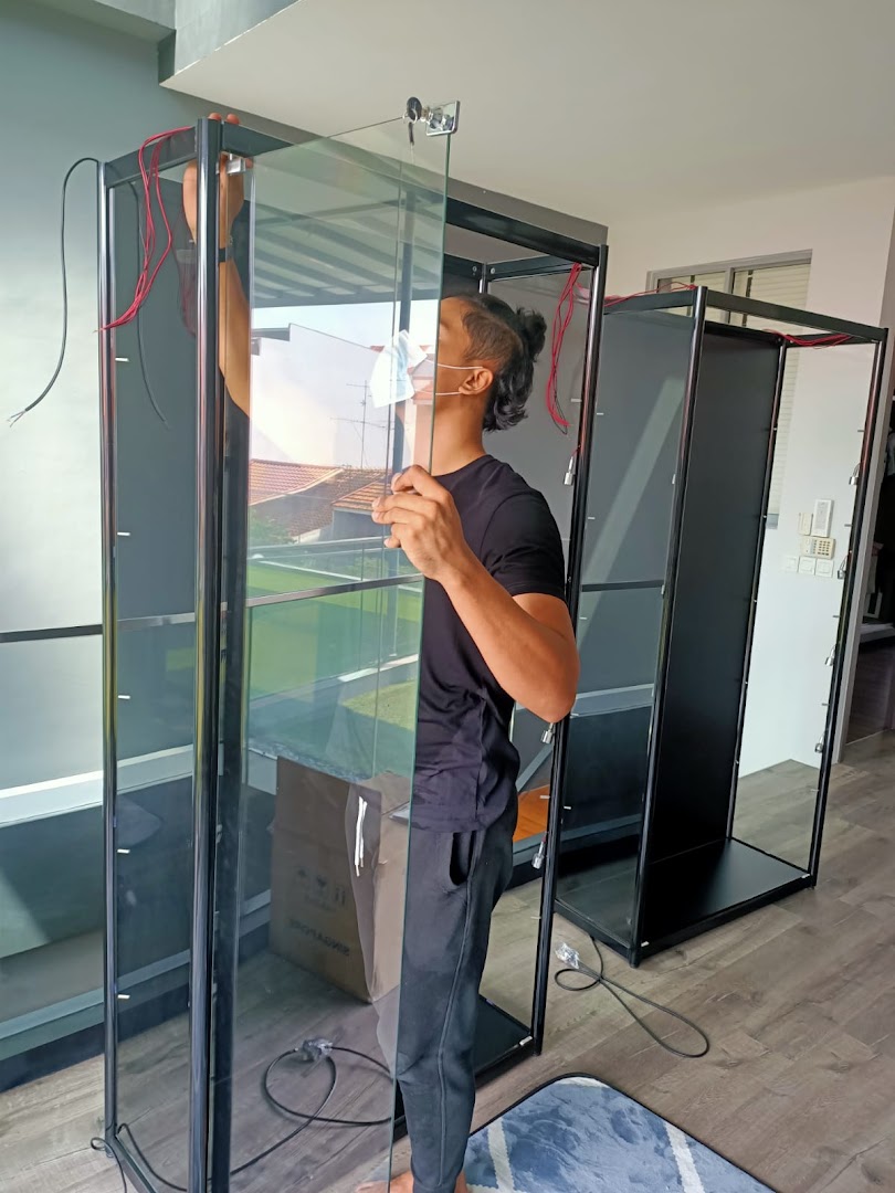 A person assembles a glass display cabinet, showcasing the setup process for retail display solutions.