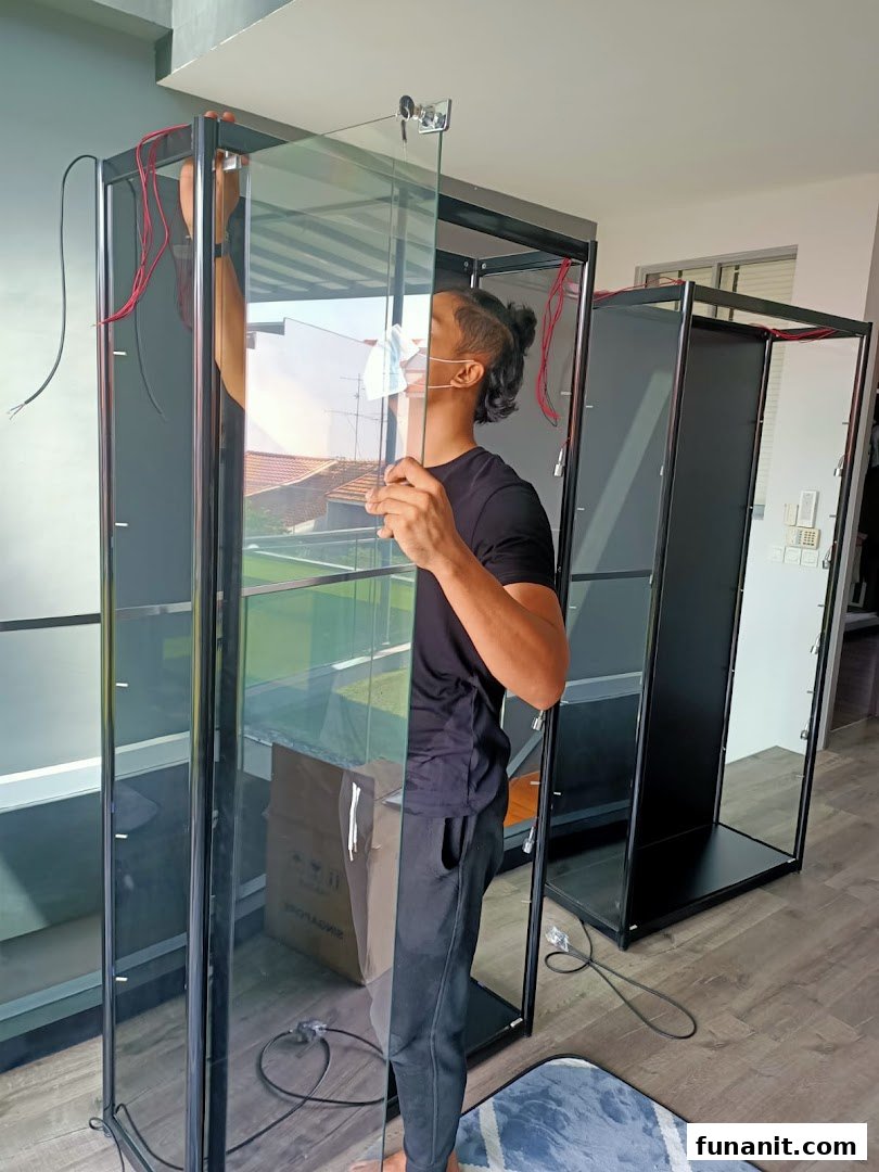 A person assembles a glass display cabinet, showcasing the setup process for retail display solutions.