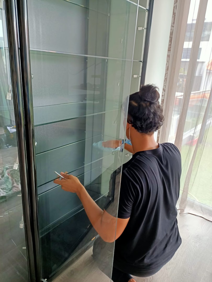 A person is assembling or cleaning a large, multi-shelf glass display cabinet.