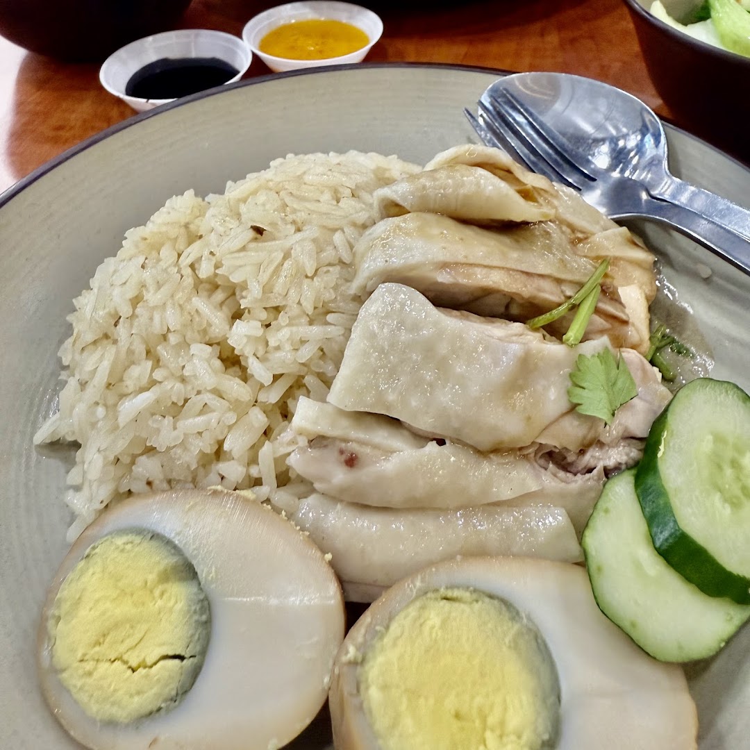 Delicious Hainanese chicken rice with tender chicken, fragrant rice, eggs, and cucumber.