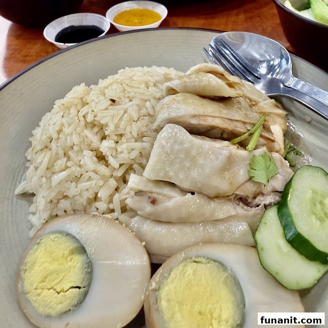 Delicious Hainanese chicken rice with tender chicken, fragrant rice, eggs, and cucumber.