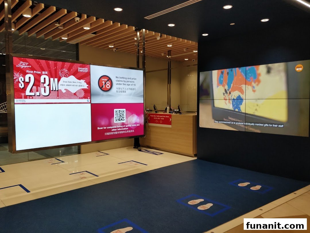 Interior view of Singapore Pools Funan Branch with large digital displays showing promotions and information.
