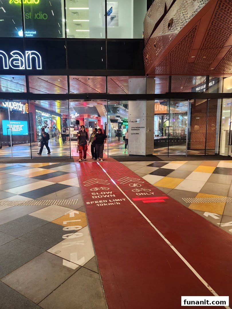 The vibrant entrance of Funan mall featuring a unique indoor cycling path and various retail outlets.