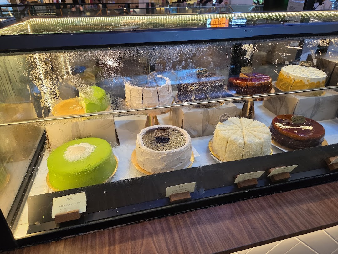 A vibrant display case showcasing a variety of delicious cakes at Sinpopo Coffee.